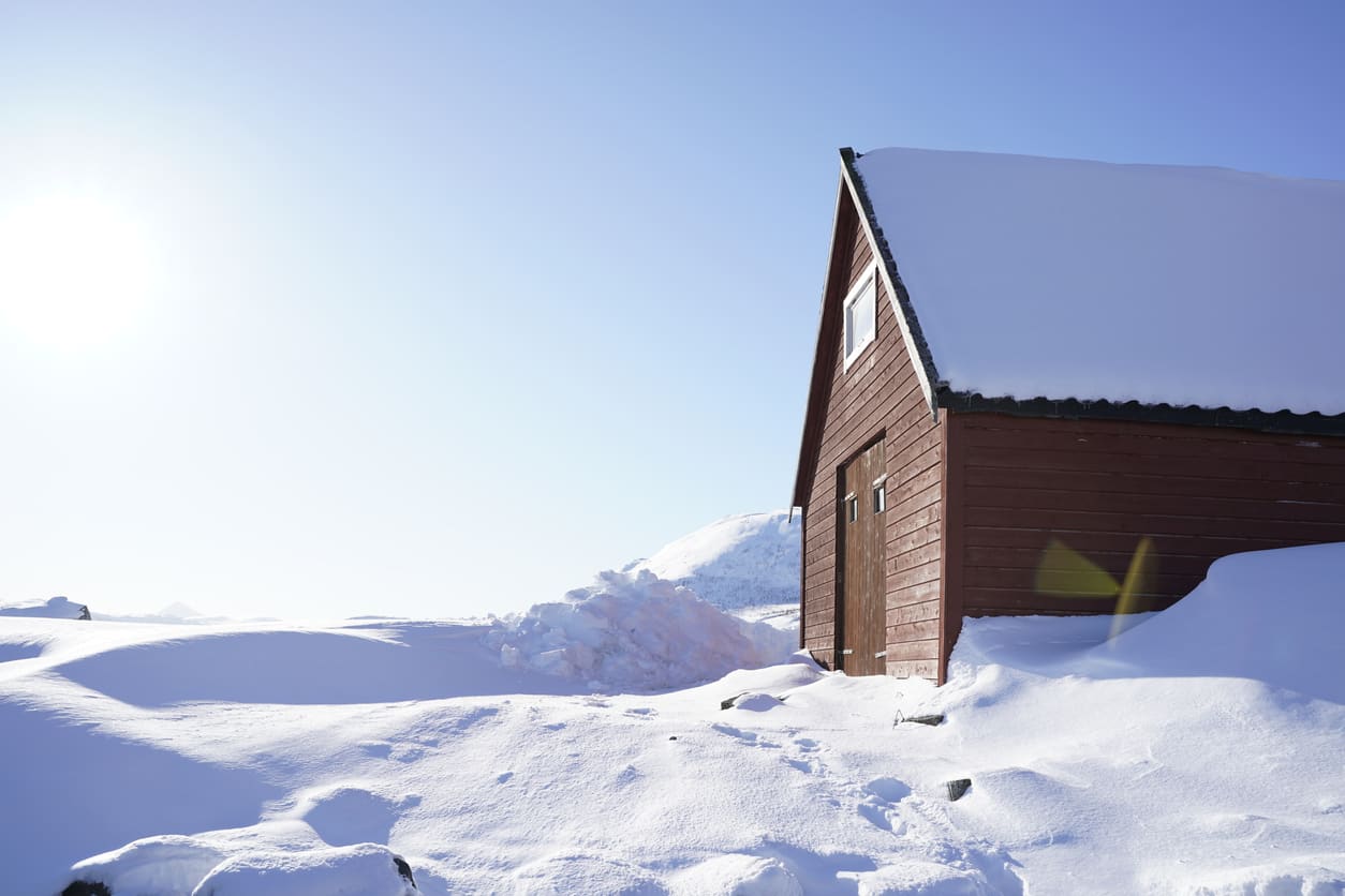 Tømmerhus i dyp snø en klar vinterdag